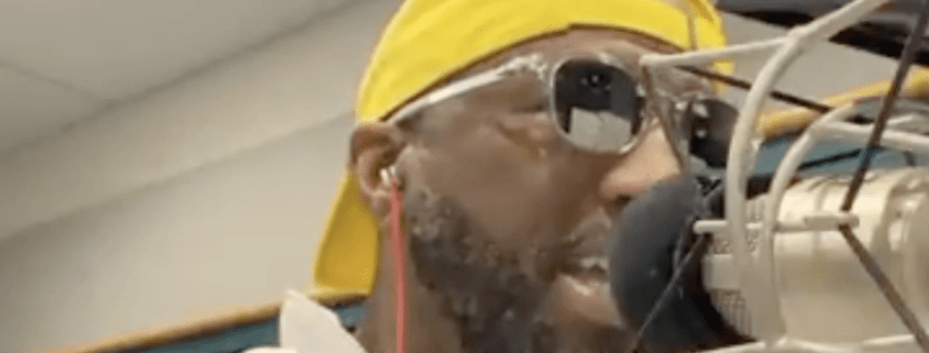 Man with headphones speaking into microphone.